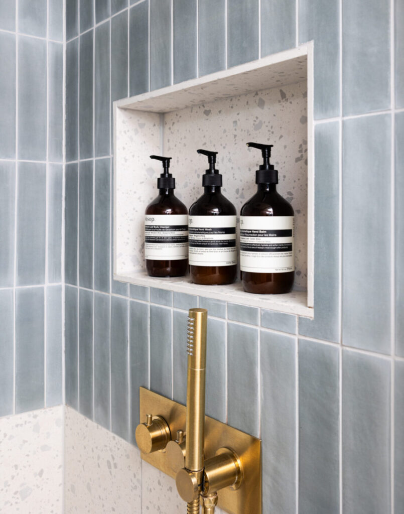 Girls en-suite with floral wallpaper matching the headboard, pink vanity unit and gold hardware