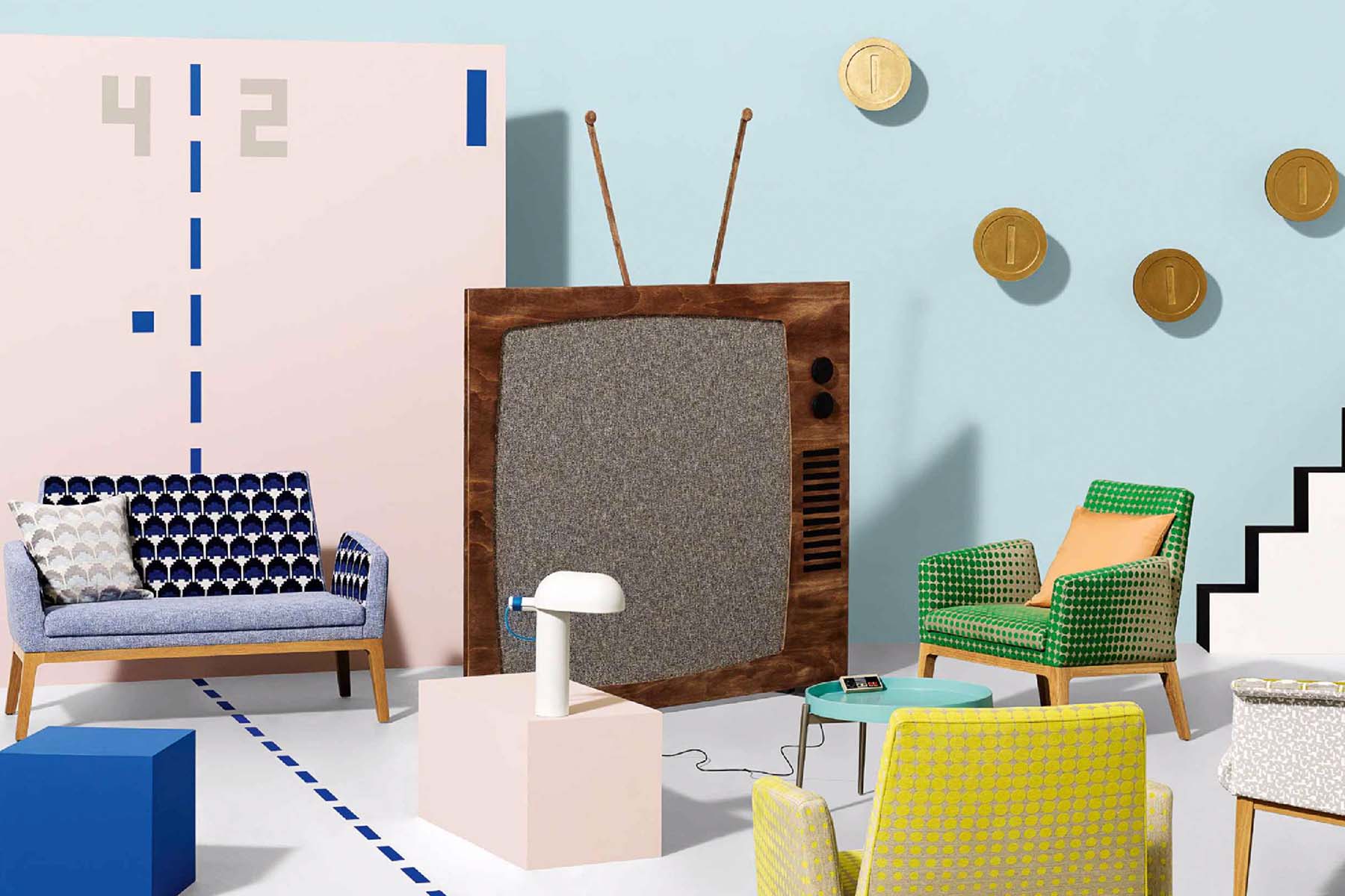 A vintage television stands prominently, connected to a modern lamp on a light-colored pedestal. Colorful chairs surround it, with graphic wall elements in a playful, bright room.