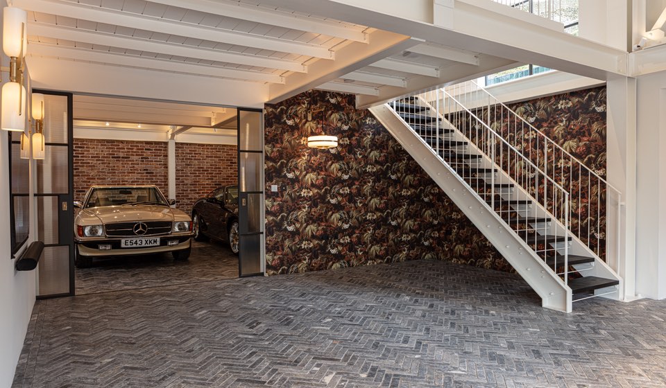 View of high end garage with exposed brick wall and herringbone stone flooring