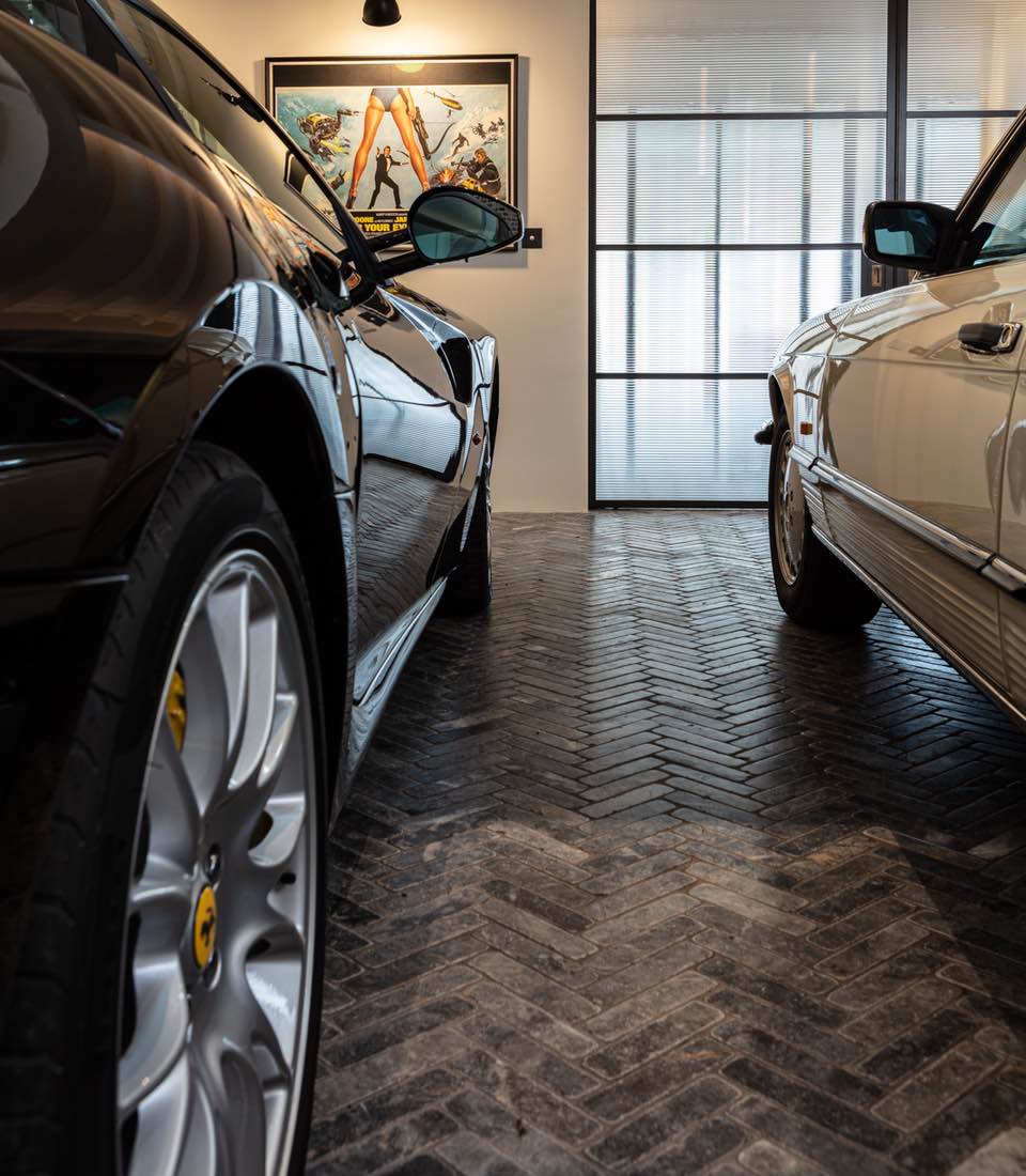 Garage with exposed brick wall, spotlights and classic cars