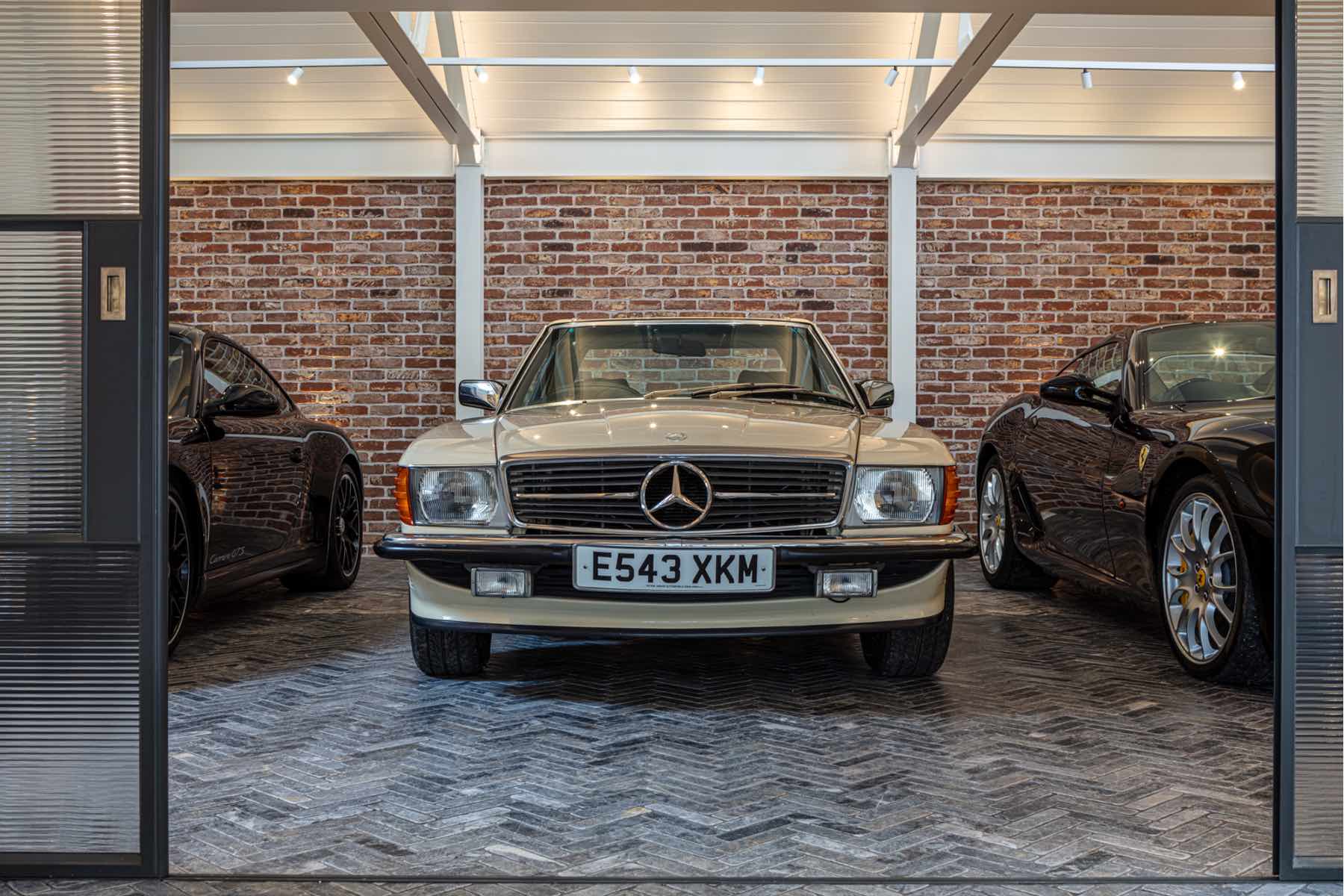 Garage with exposed brick wall, spotlights and classic cars