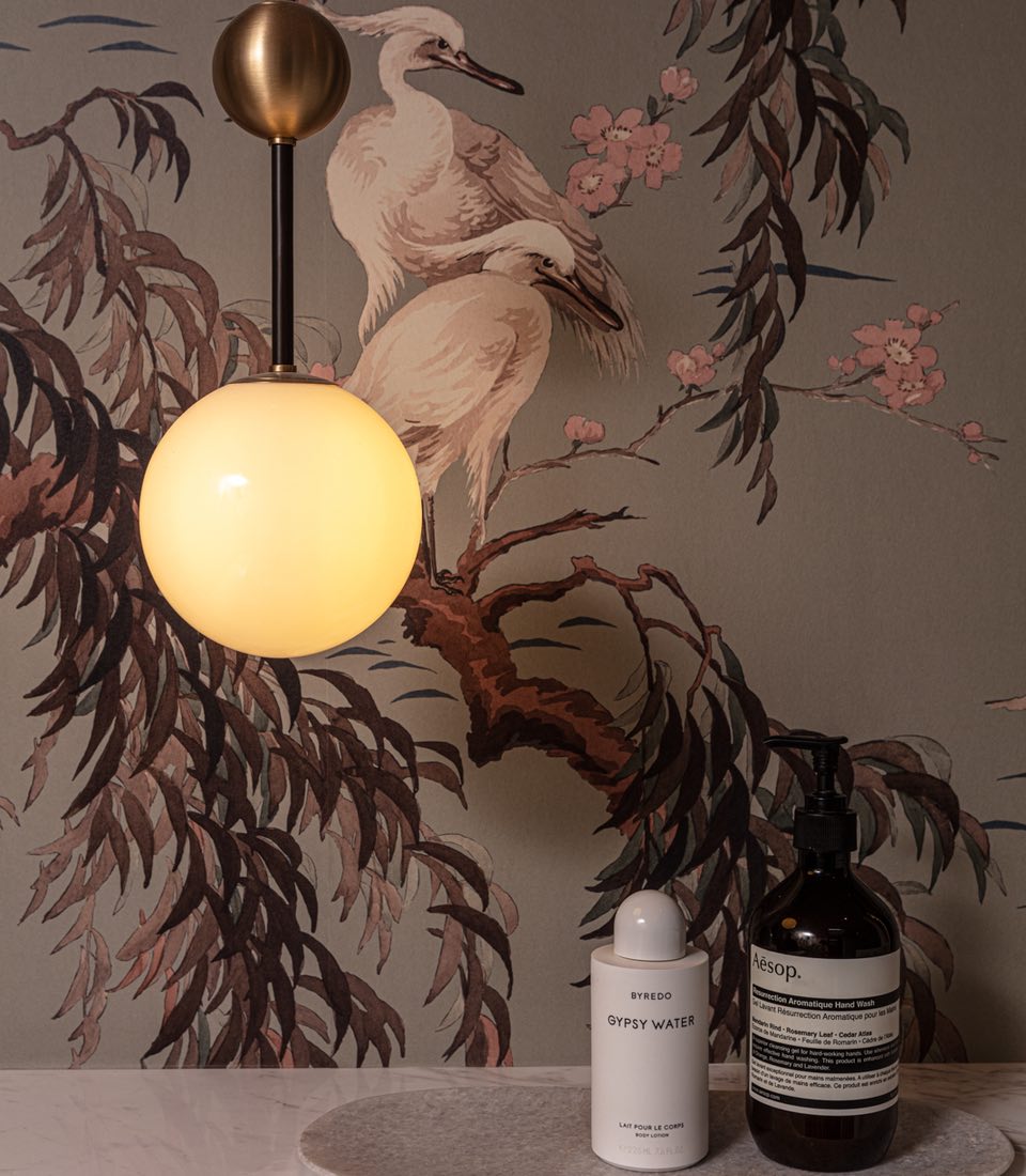 Unique brass lighting fixture against illustrative wallpaper