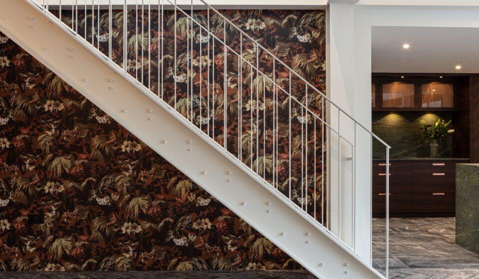 White metal staircase against backdrop of decorative wallpaper