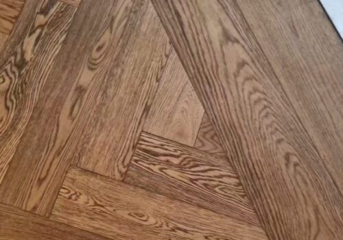 Herringbone timber wood floor with straight plank border against marble flooring