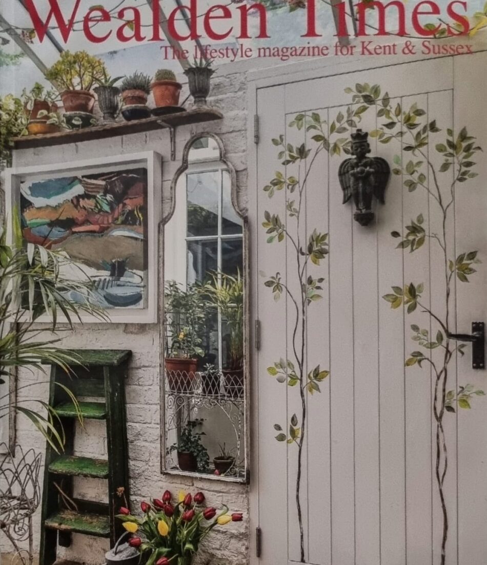 A magazine cover featuring a white door adorned with floral designs, a mirror reflecting greenery, and potted plants. The title "Wealden Times" is prominently displayed at the top.