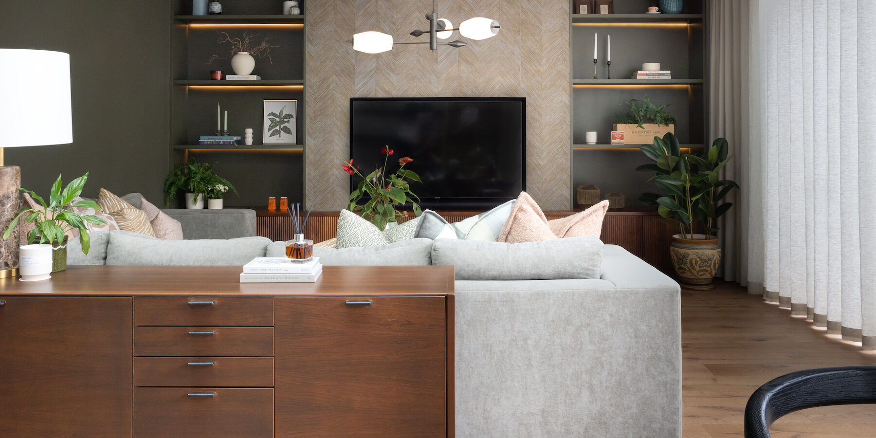 Contemporary Snug Shelving Designed with Bespoke Joinery by Pfeiffer Design. Warm wood joinery with dark green paint in recess and textured wallpaper with warm LED lighting design