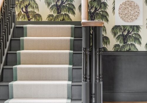 Art Deco Inspired Entrance Hall designed by Pfeiffer Design. Art deco inspired wallpaper, renovated staircase with painted treads and spindles in dark green, added panelling and artwork, chevron runner
