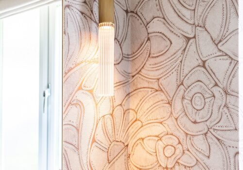 Art Deco Inspired Guest Bathroom/ Downstairs WC designed by Pfeiffer Design. Textured wallpaper in pale pink with half height tiling below, deep burgundy vanity unit with gold accent handles, warm wall lighting in a guest downstairs bathroom WC