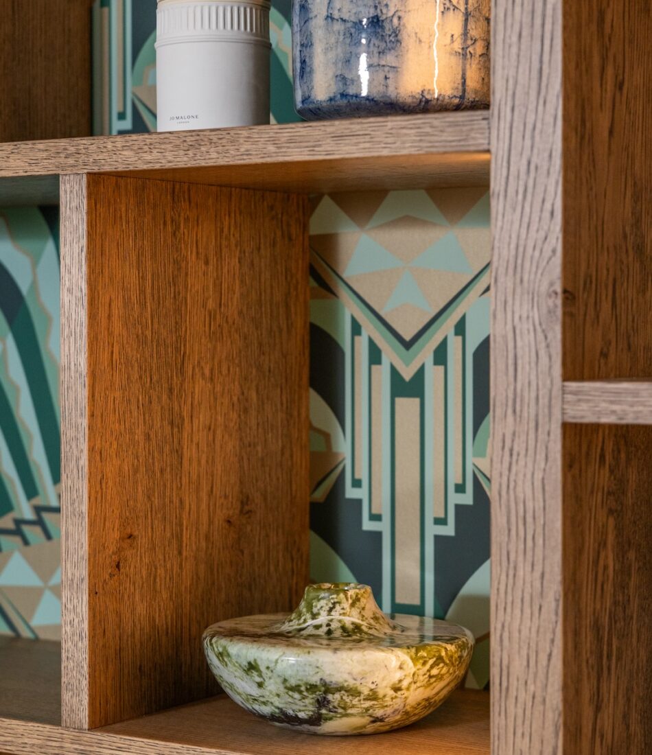Art Deco Inspired Bespoke Bar and Library made by our bespoke joiners, designed by Pfeiffer Design. Art deco wallpapered insert within light timber open cabinetry, hints of gold through the backing and handles, and LED lighting for a warm but subtle glow