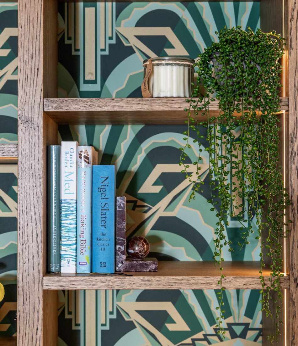 Art Deco Inspired Bespoke Bar and Library made by our bespoke joiners, designed by Pfeiffer Design. Art deco wallpapered insert within light timber open cabinetry, hints of gold through the backing and handles, and LED lighting for a warm but subtle glow