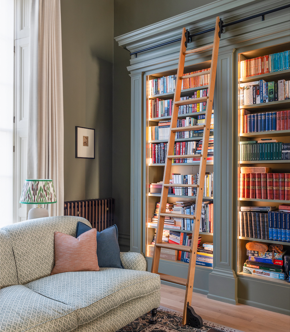 Home library, tall book shelves with warm LED strip lighting and rolling ladder