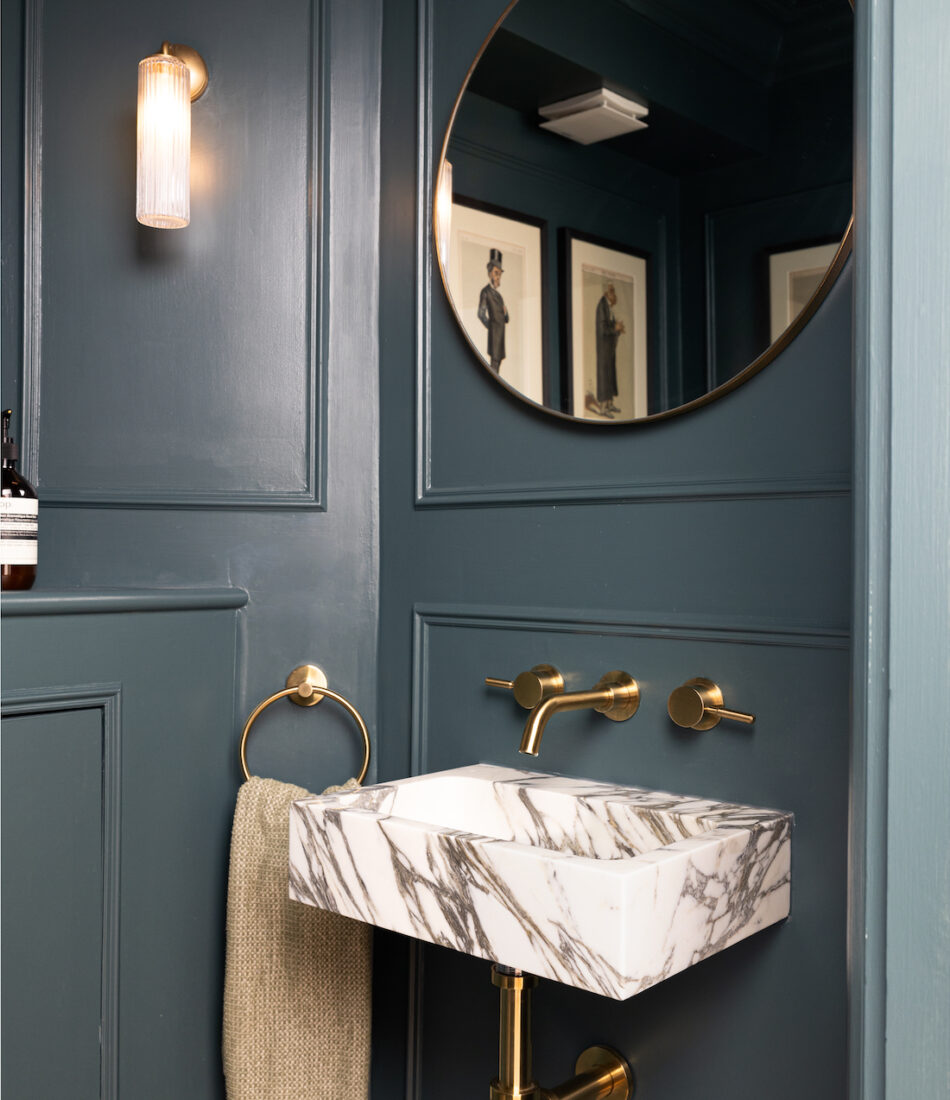 Small WC with dark walls, gold hardware and marble sink