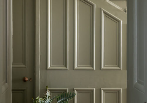 Traditional panelled staircase in green paint with large plant