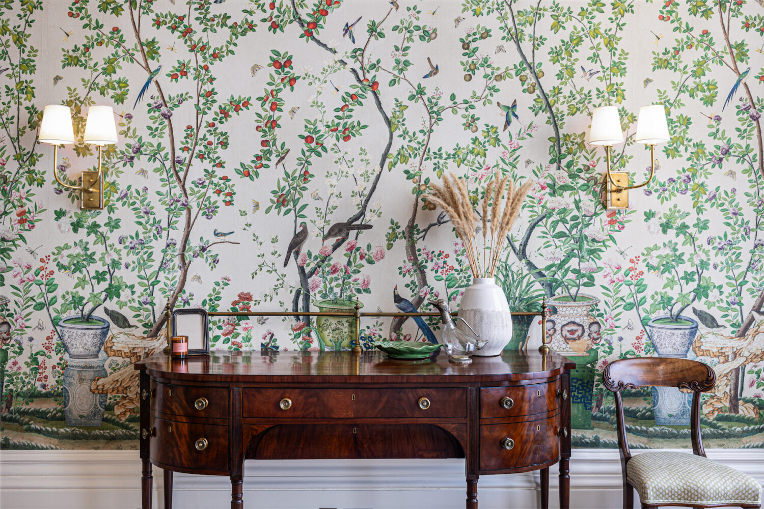 Busy patterned foliage wallpaper behind vintage dark wooden console, vanity