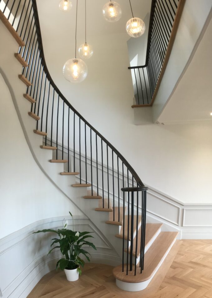 Winding staircase with black hand rail and wooden steps.