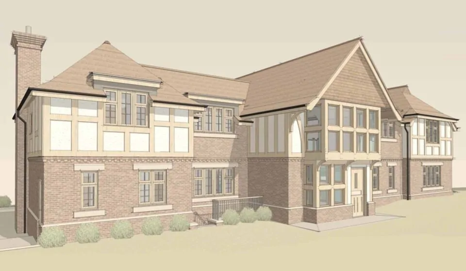 A large residential building features varied architectural styles, including brick and wood elements. It has multiple steep roofs and several windows, situated in a grassy area with shrubs.