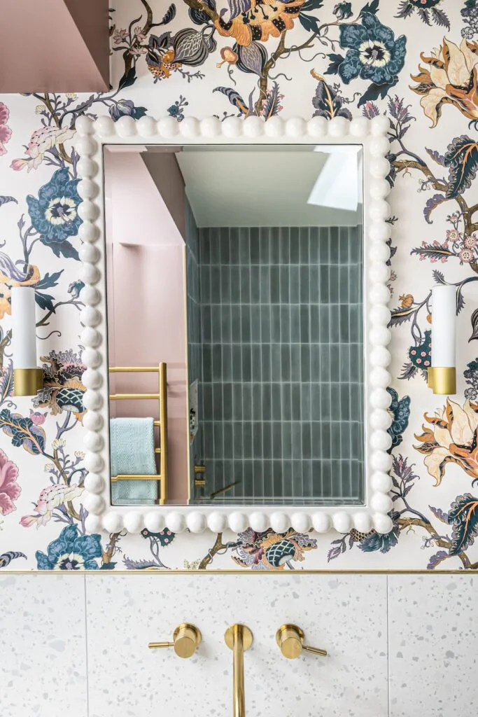 Girls en-suite with floral wallpaper matching the headboard, pink vanity unit and gold hardware