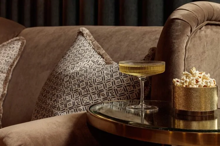 Close up of cocktail next to velvet sofa in cinema room