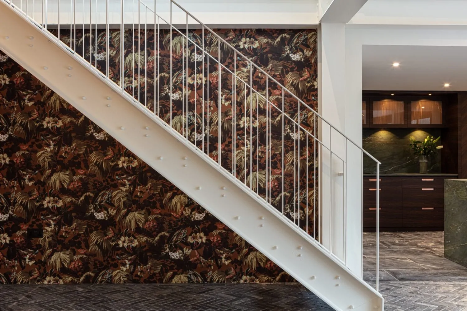 White metal staircase against backdrop of decorative wallpaper