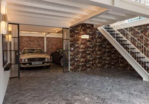 Entrance to garage with classic cars and herringbone stone flooring