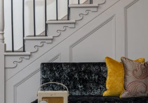 Sofa and table at base of stairway - period curved details on stair, molding and banister details.