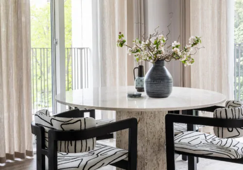 Обеденный стол в современном стиле в нейтральных тонах для городской квартиры, геометрические черно-белые стулья и восьмиугольный стол из травертина