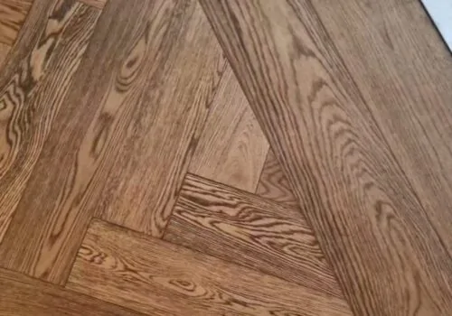Herringbone timber wood floor with straight plank border against marble flooring