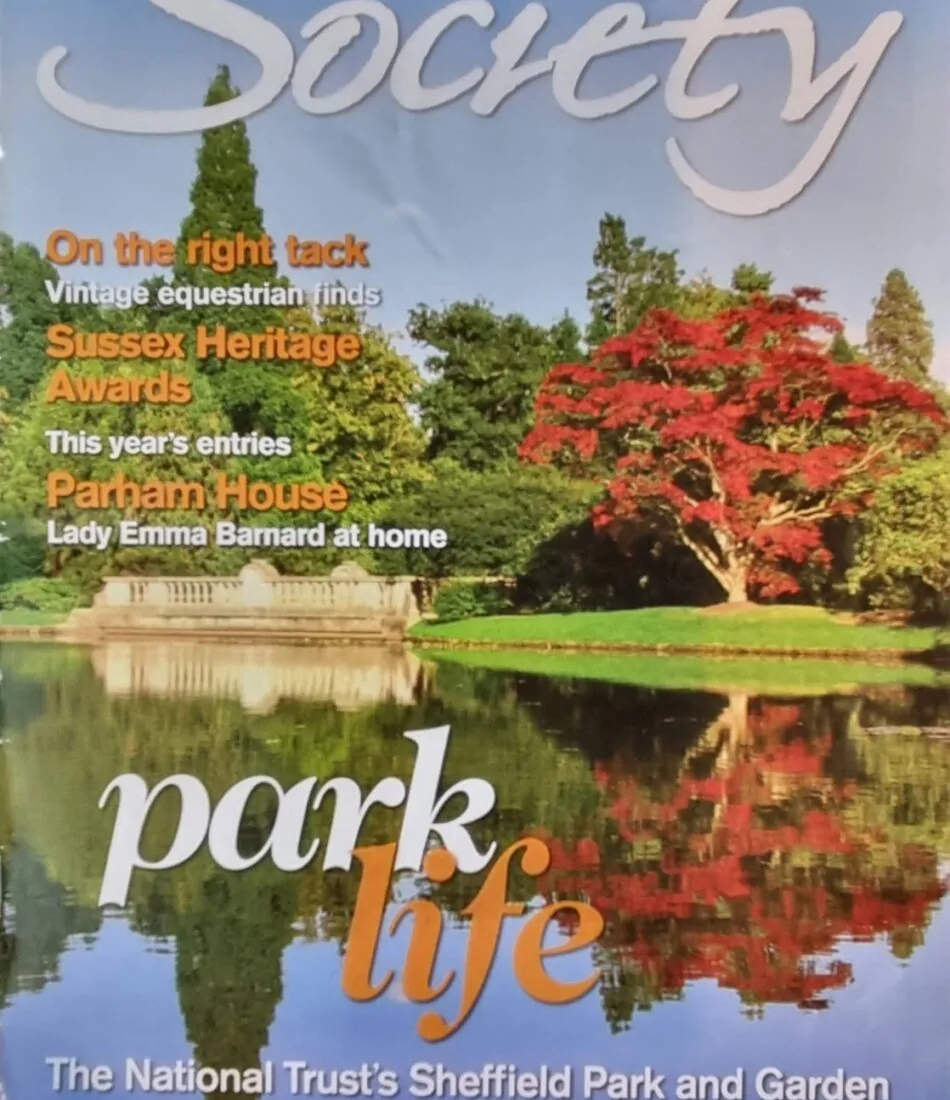 A magazine cover features the title "Sussex Society" at the top, dated July 2023. Below, the phrase "park life" is highlighted, with a subtitle about Sheffield Park and Garden. The background shows greenery and colorful foliage reflecting in water.