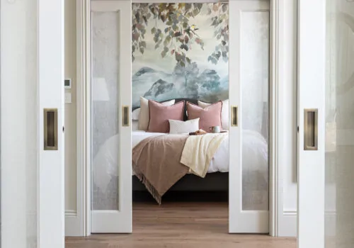 Современная спальня с изголовьем кровати, изготовленным на заказ, и обоями Mural от Pfeiffer Design. Нейтральная цветовая палитра и тёплое освещение.