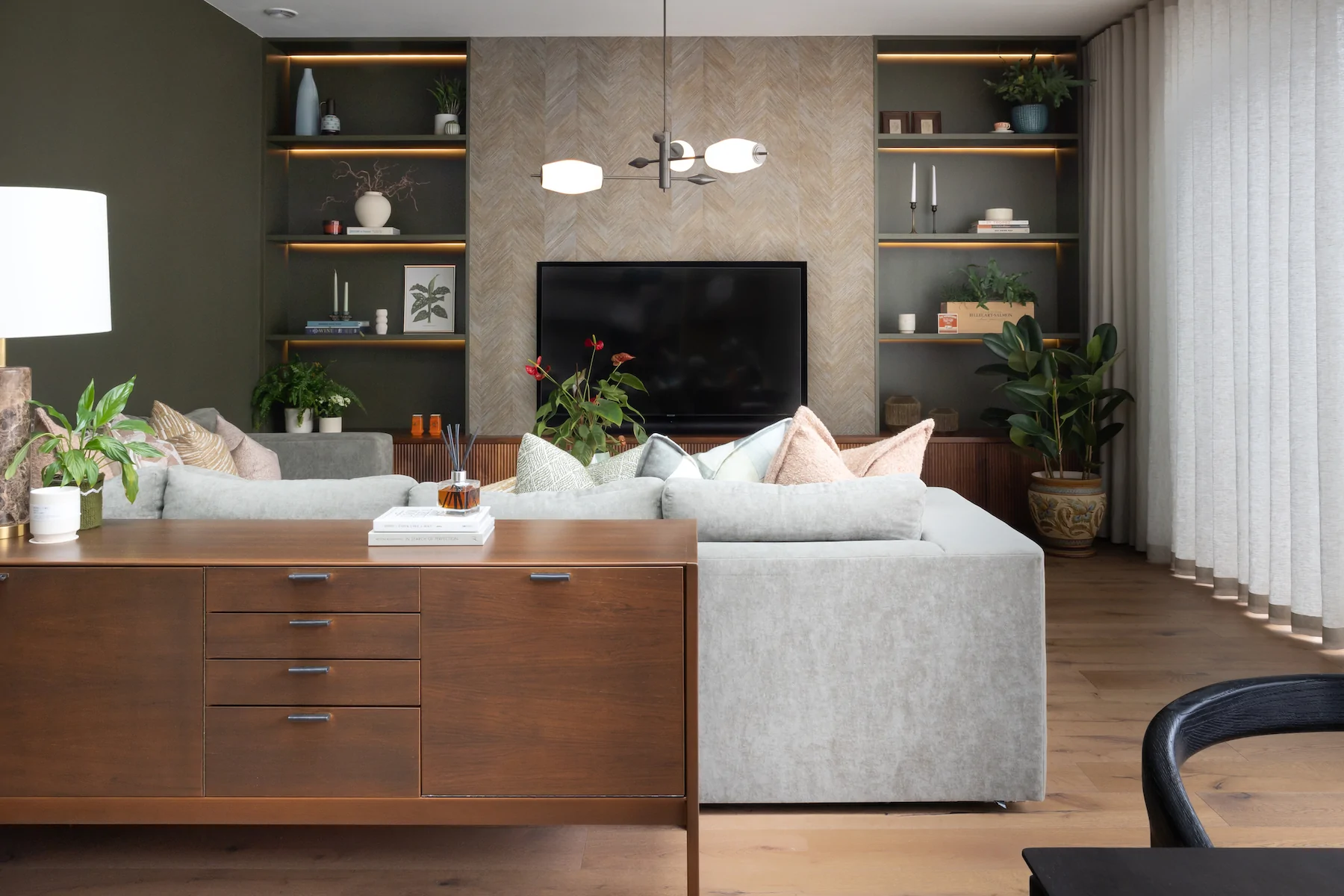 Contemporary Snug Shelving Designed with Bespoke Joinery by Pfeiffer Design. Warm wood joinery with dark green paint in recess and textured wallpaper with warm LED lighting design