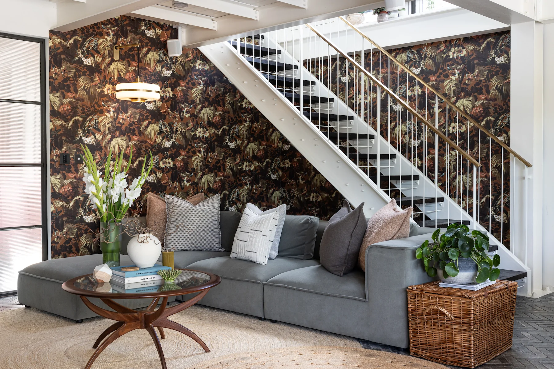 Pfeiffer Design studio with pattern bold wallpaper and grey sofa with pops of green and pink through foliage and cushions