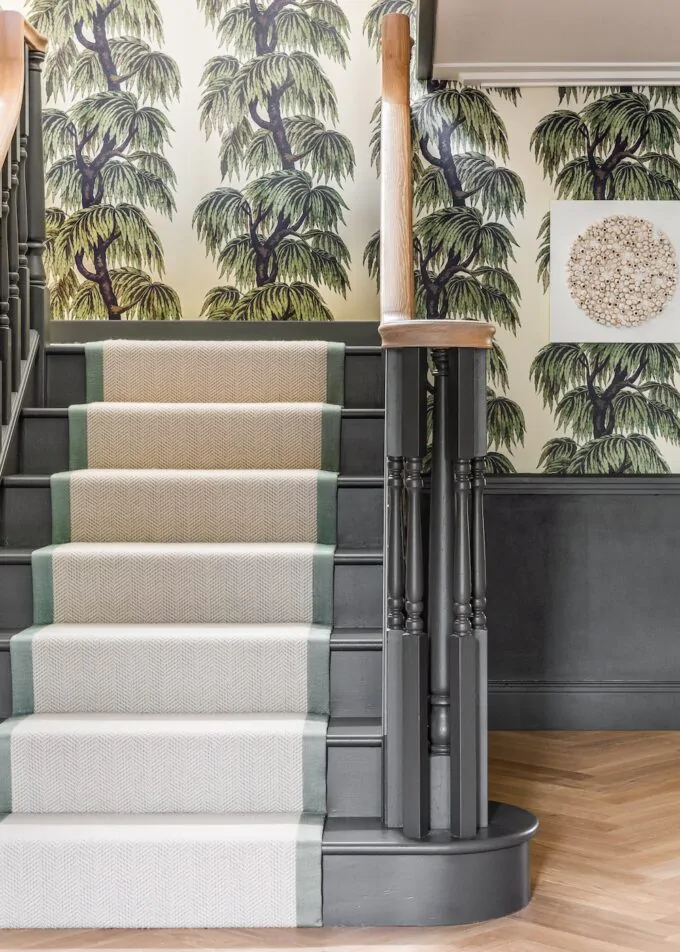 Art Deco Inspired Entrance Hall designed by Pfeiffer Design. Art deco inspired wallpaper, renovated staircase with painted treads and spindles in dark green, added panelling and artwork, chevron runner