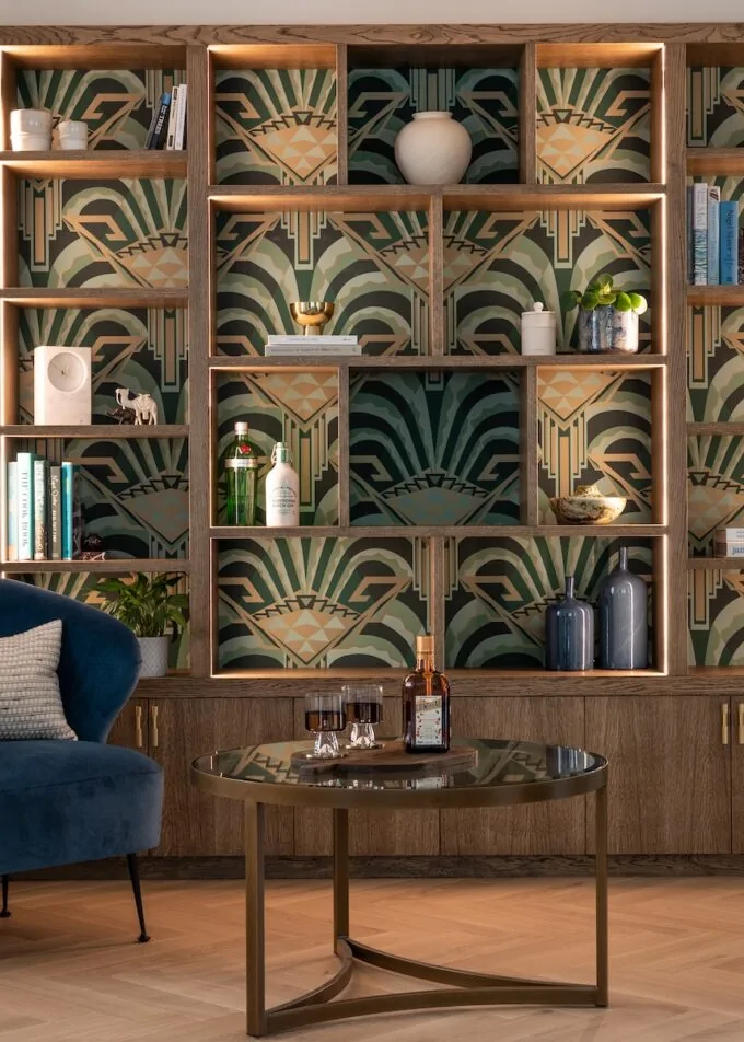 Art Deco Inspired Bespoke Bar and Library made by our bespoke joiners, designed by Pfeiffer Design. Art deco wallpapered insert within light timber open cabinetry, hints of gold through the backing and handles, and LED lighting for a warm but subtle glow