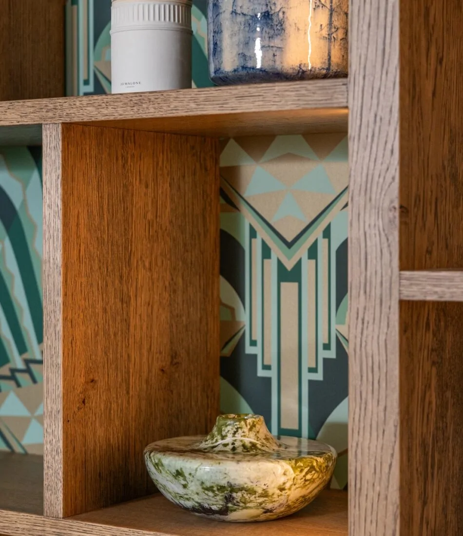 Art Deco Inspired Bespoke Bar and Library made by our bespoke joiners, designed by Pfeiffer Design. Art deco wallpapered insert within light timber open cabinetry, hints of gold through the backing and handles, and LED lighting for a warm but subtle glow