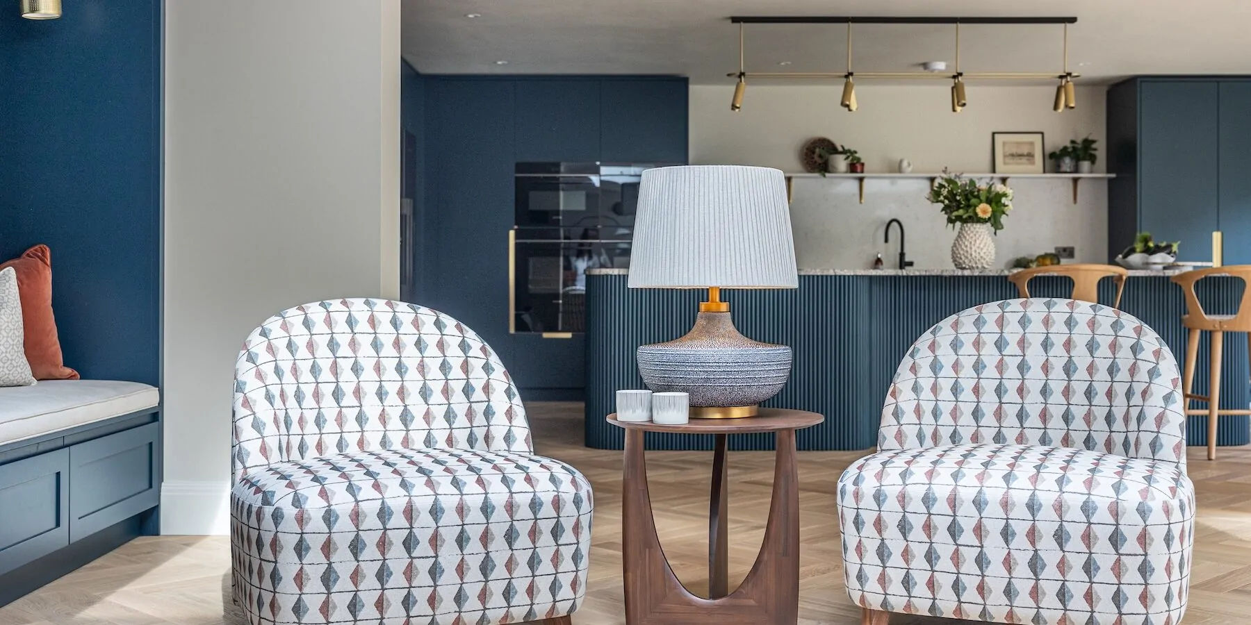 Bespoke upholstered chairs with geometric pattern in cosy snug, background is bespoke kitchen joinery. open plan living for contemporary family life