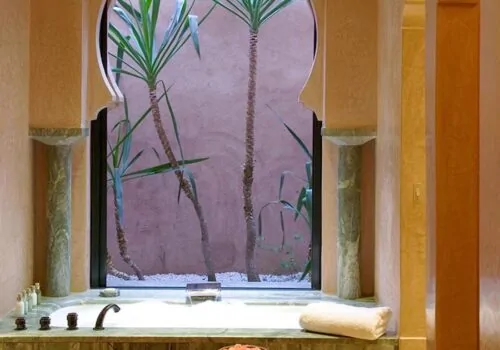 Hotel bathroom design with marble bath looking out window to palm trees