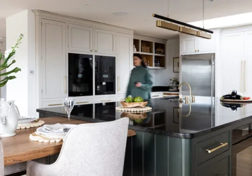 Kitchen design with deep green island units, black worktop and gold pendant light
