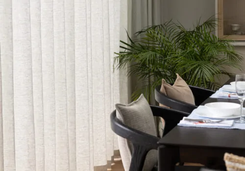 Dining Room close up of curtain wave texture, showing dining table with black wood chairs and decorative cushions