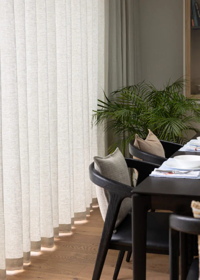 Dining Room close up of curtain wave texture, showing dining table with black wood chairs and decorative cushions