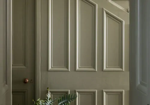 Traditional panelled staircase in green paint with large plant