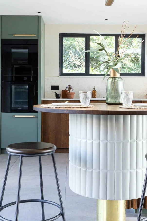Contemporary kitchen with green cabinets, curved breakfast bar and wooden finishes.