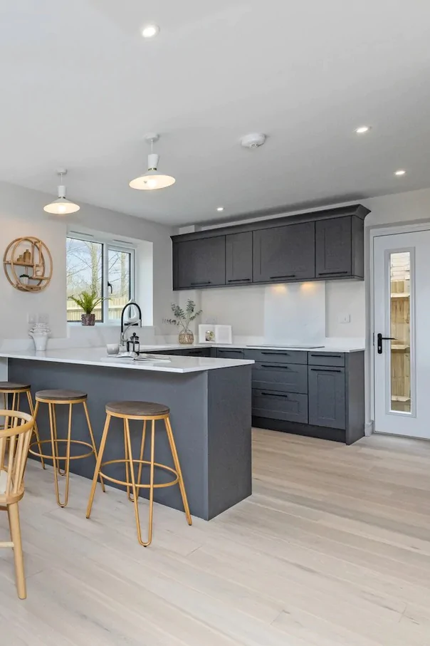 Contemporary kitchen with grey cabinets, breakfast bar and wooden stools.